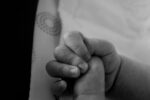 adult hand holding tiny baby hand