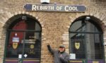 ralph greco jr pointing to "rebirth of cool" sign