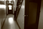 interior of apartment building, looking down hallway to exit w/ stairwell on the side