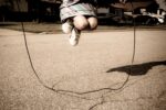 girl jumping rope, only her feet and knees are in the frame, with the rope below.