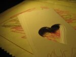 kids scribbled crayon drawing with papers with hearts cut out on top