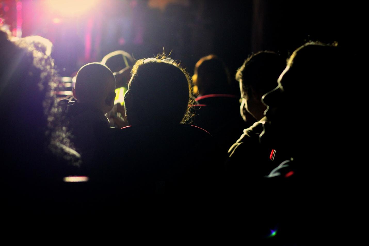 Audience in a dark room with light emanating from stage