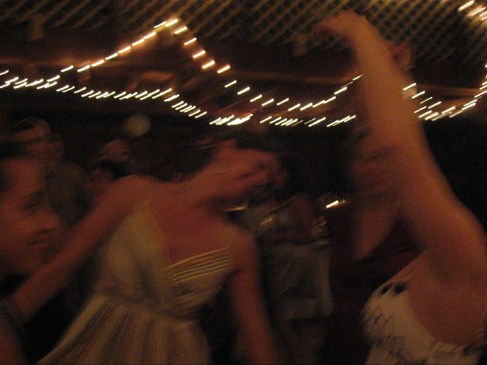 A group of people dancing at a party; intentionally blurry to show motion; string of lights above