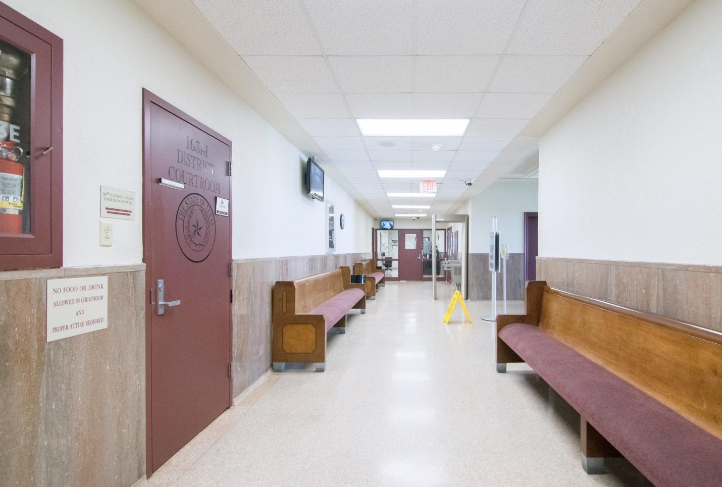 Long shot of a hallway with benches; stark government looking building