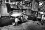 A barber shop with a chair; older-style wooden cabinetry and vintage chairs