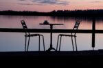 two chairs and a small table, lakefront, at sunset