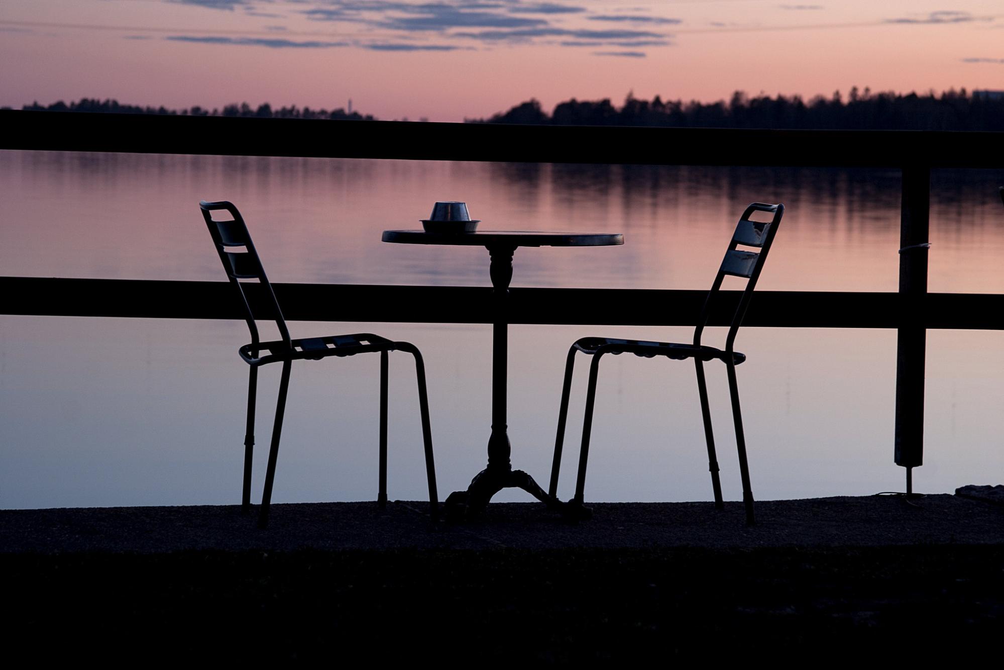 two chairs and a small table, lakefront, at sunset