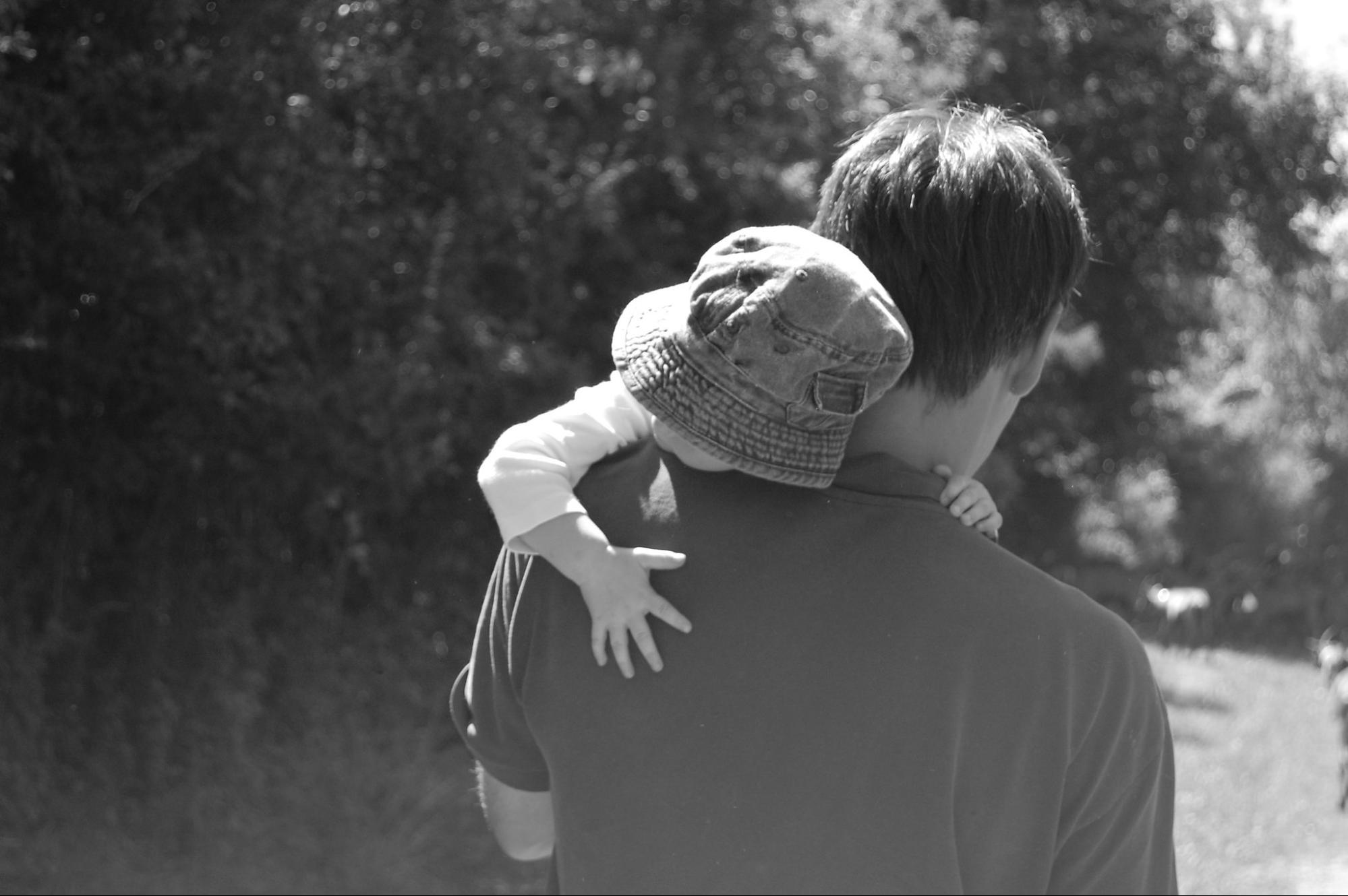 father holding baby in bucket hat over his shoulder, facing away from camera, from the Hippocampus Mag story by Andreea Boboc