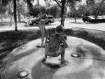 three kids playing baseball; sculptures in an outdoor public art display