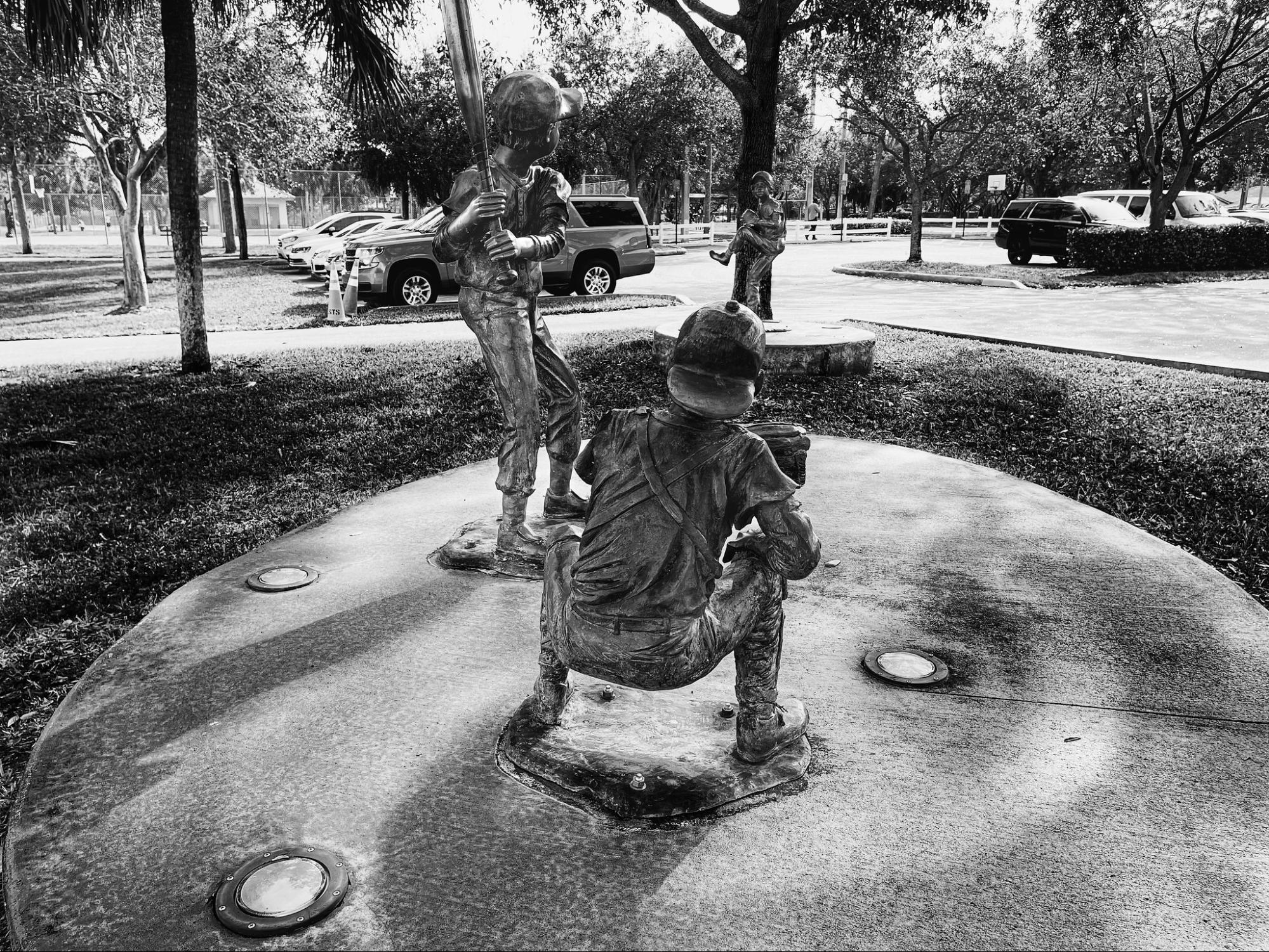 three kids playing baseball; sculptures in an outdoor public art display