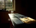 table in kitchen with sun shining in, tongs and pitcher on table